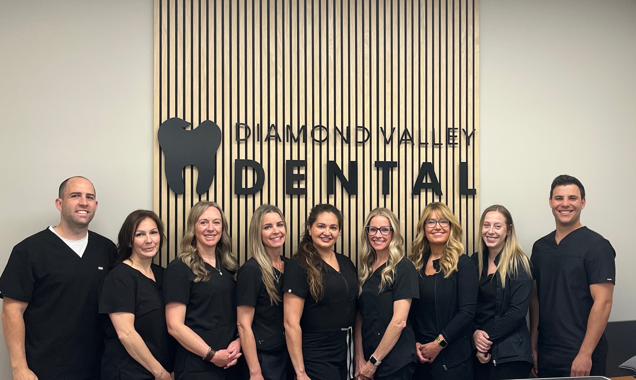 Diamond Valley Dental team in front of the clinic sign